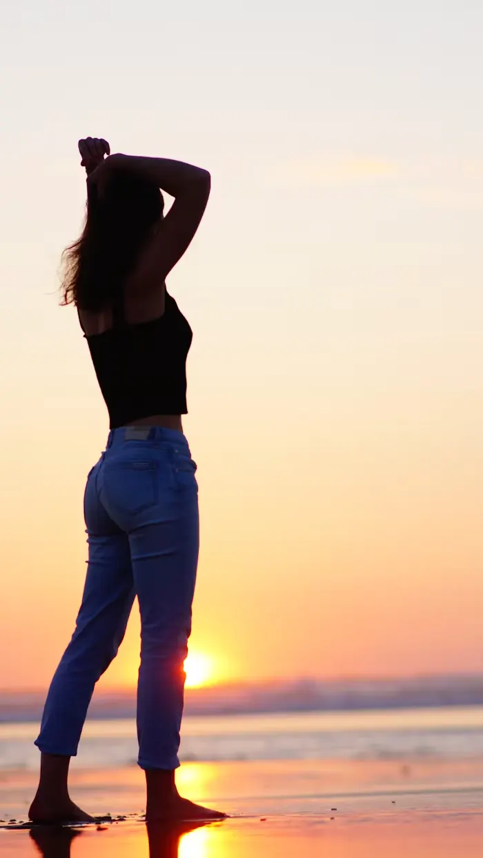 Silhouette standing by the water at sunset